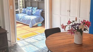 Ein Zimmer mit einem Bett, einem Tisch mit einer Vase und Blick auf einen Balkon.