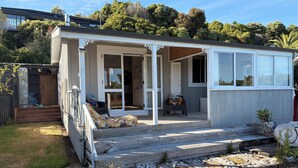 Ein kleines, eingeschossiges Haus mit Veranda, Schiebetür und einem kleinen Garten.