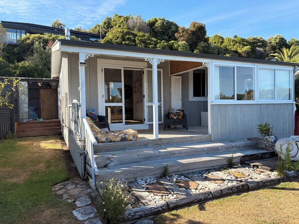 A small, single-story house with a porch, a sliding glass door, and a small garden area.