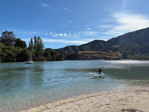 A lake with a boat, kayaks, and a person paddling.