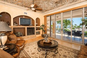 A living room with a fireplace, television, and outdoor patio with tables and chairs. - Casa Blanca Villa 9 | 3BR Condo | Sleeps 6 (Puerto Peñasco)