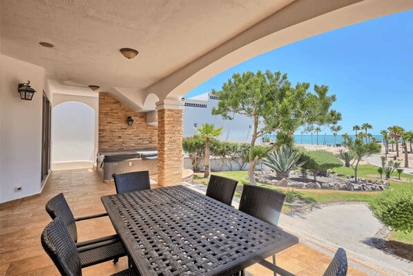 Eine Terrasse im Freien mit Tisch und Stühlen, einer Steinmauer und Blick auf das Meer.