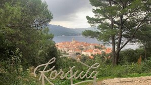 A sign with 'Korsula' written on it, surrounded by greenery and overlooking a coastal town with red-roofed buildings. - Apartment F1 in Lumbarda with pool near beach (Lumbarda)