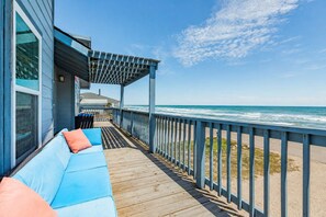 A wooden deck with a blue railing, a blue sofa with orange cushions, and a view of the ocean. - Chelsea By The Sea - Breathtaking Views of Blue! (Freeport)