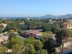 Eine Küstenstadt mit Gebäuden, Bäumen und Blick auf das Meer sowie einen Hügel in der Ferne.