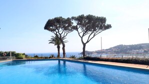 Una piscina cristallina blu con vista sul mare e sulle colline sullo sfondo.