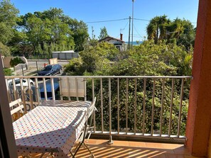 A balcony with a table and chairs, a view of the sea, and surrounding greenery. - Duplex apartment, sea view, parking - 4 guests (Argelès-sur-Mer)
