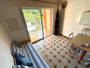 Ein Zimmer mit einer Couch, einem Tisch und Blick durch eine Glastür zu einem Außenbereich.