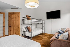 A bunk bed with a TV above it, a wooden door, and a sofa with pillows. - Luxury Penthouse Unparalleled Views & Comfort (Canmore)
