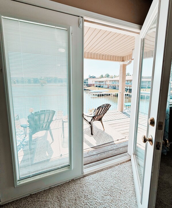 Ein Zimmer mit einer Schiebetür zu einer Terrasse im Freien, ausgestattet mit einem Holzboden und einem Stuhl.