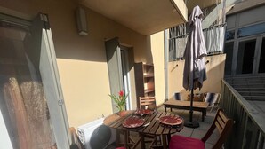 Ein Balkon mit Esstisch, Stühlen, einem Topfpflanzen und einem Ventilator.
