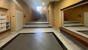 Ein Korridor mit einer Treppe, gefliestem Boden und einem Feuerlöscher an der Wand.
