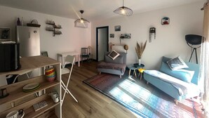 Ein modernes Wohnzimmer mit Holzboden, einer Couch, einem Esstisch und einem Fernseher.