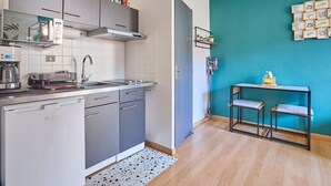 A compact kitchen with a dishwasher, a coffee machine, and a toaster. There's a teal accent wall and a small table with chairs. - Studio in Barbotan-les-Thermes, Wi-Fi, Pets Allowed (Barbotan-les-Thermes)