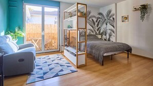 A modern bedroom with a bed, a sofa, a ceiling fan, and a view of the outside. - Studio in Barbotan-les-Thermes, Wi-Fi, Pets Allowed (Barbotan-les-Thermes)