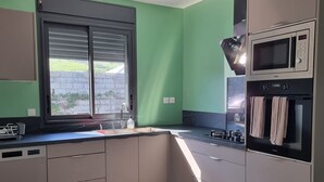 Eine Küche mit Fenster, Mikrowelle und Herd.