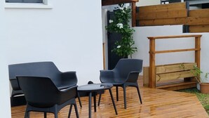 Eine Holzterrasse mit zwei schwarzen Stühlen und einem kleinen Tisch.