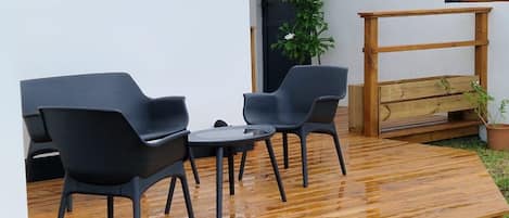 Una terraza de madera con dos sillas negras y una mesa pequeña.