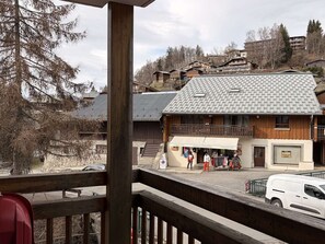 A wooden building with a balcony, a sign for a fabric store, and a parking area. - Convenient apartment near ski lifts - 4 guests (Arâches-la-Frasse)