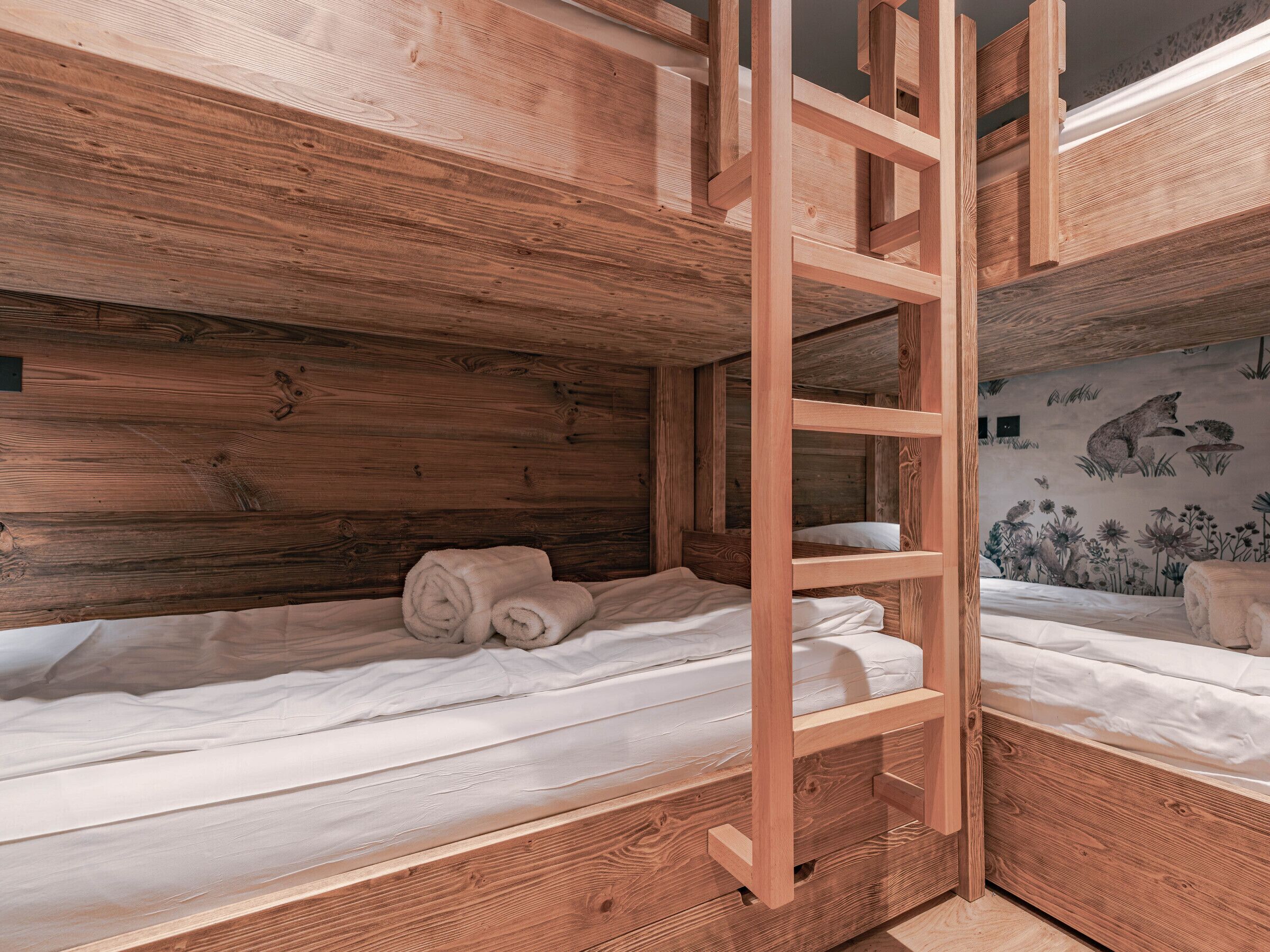 Un lit superposé en bois, avec une échelle et une fresque murale.
