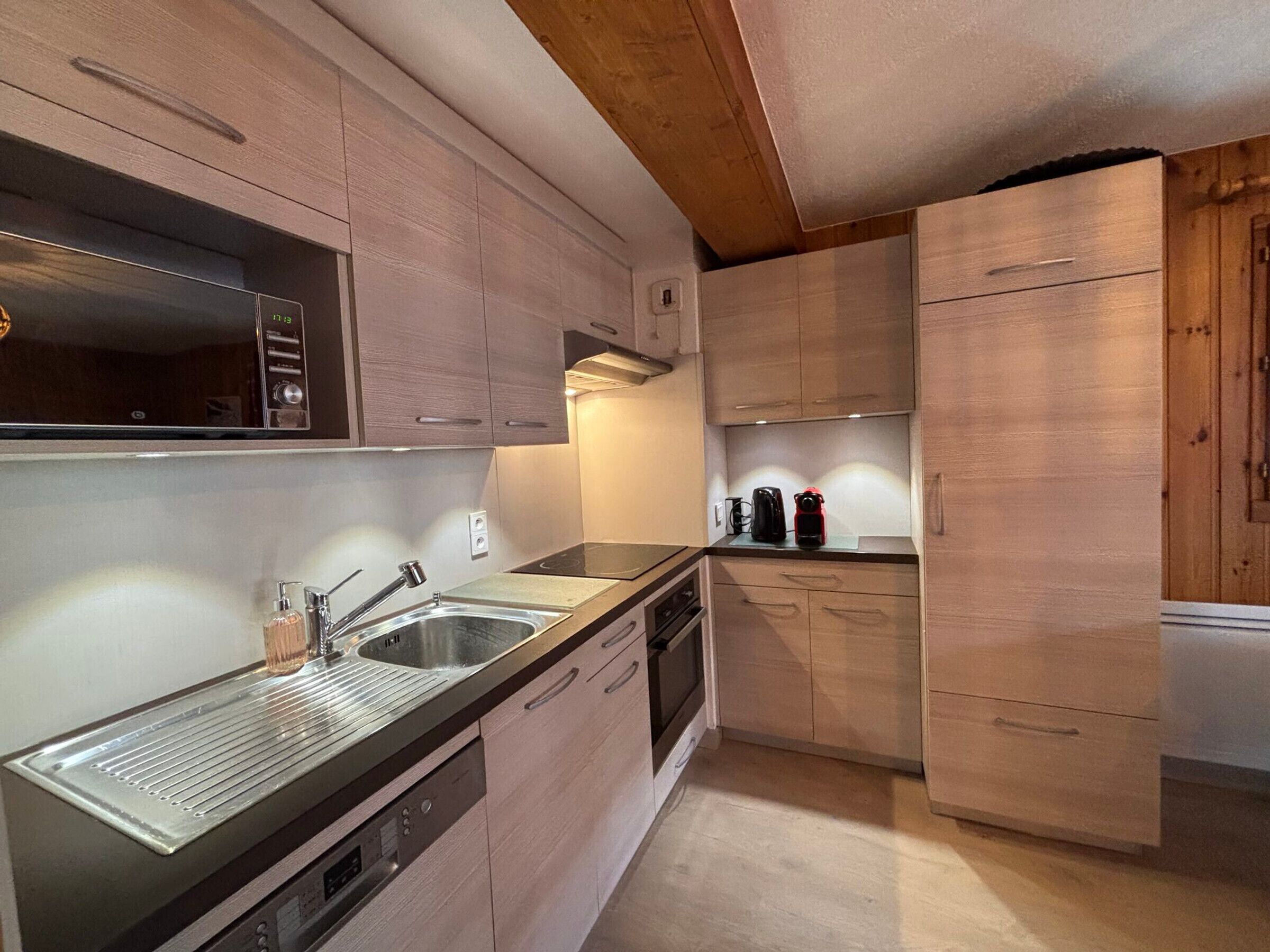 A modern kitchen with stainless steel appliances, wooden cabinets, and a built-in oven.