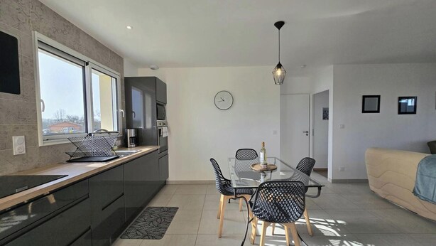 Une cuisine moderne avec un coin repas, un canapé et une horloge au mur.