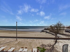 A beach view with a paved area, outdoor seating, and a clear sky. - Renovated studio cabin, sea view - 4 guests (Le Grau d'Agde)