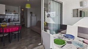 En moderne lejlighed med spiseplads, tekøkken og en skydedør til en balkon.