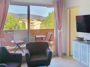 A room with a balcony, a television, and a table with chairs. - Air-conditioned studio cabin - Bormes-les-Mimosas (Bormes-les-Mimosas)