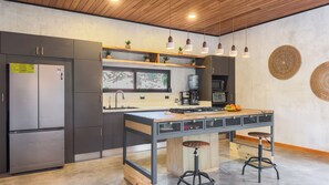 A modern kitchen with a central island, stainless steel appliances, and pendant lighting. - House surrounded by nature only 20 min from Jaco| Pet friendly | Swimming pool| Groups (Esterillos Oeste)