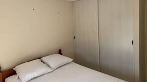 Quarto com cama, guarda-roupa e luminária no teto.