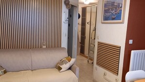 Ein Wohnzimmer mit einer Couch, einem Heizkörper, einem Sessel und einer Tür zu einem anderen Raum.