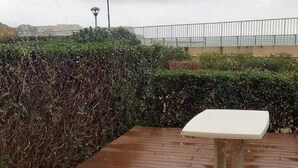 Eine Holzterrasse mit einem weißen Tisch und einem Metall-Lampenpfosten im Hintergrund.