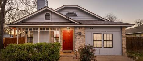 A single-story house with a red front door, a garage, and a brick exterior.
