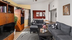 Ett modernt vardagsrum med en grå soffa, en svart- och vitrandig matta och en takfläkt.