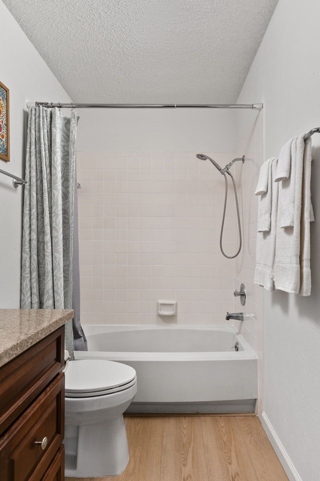 Ein Badezimmer mit Toilette, Badewanne, Dusche und einem Holzlagerflächen-Waschtisch.