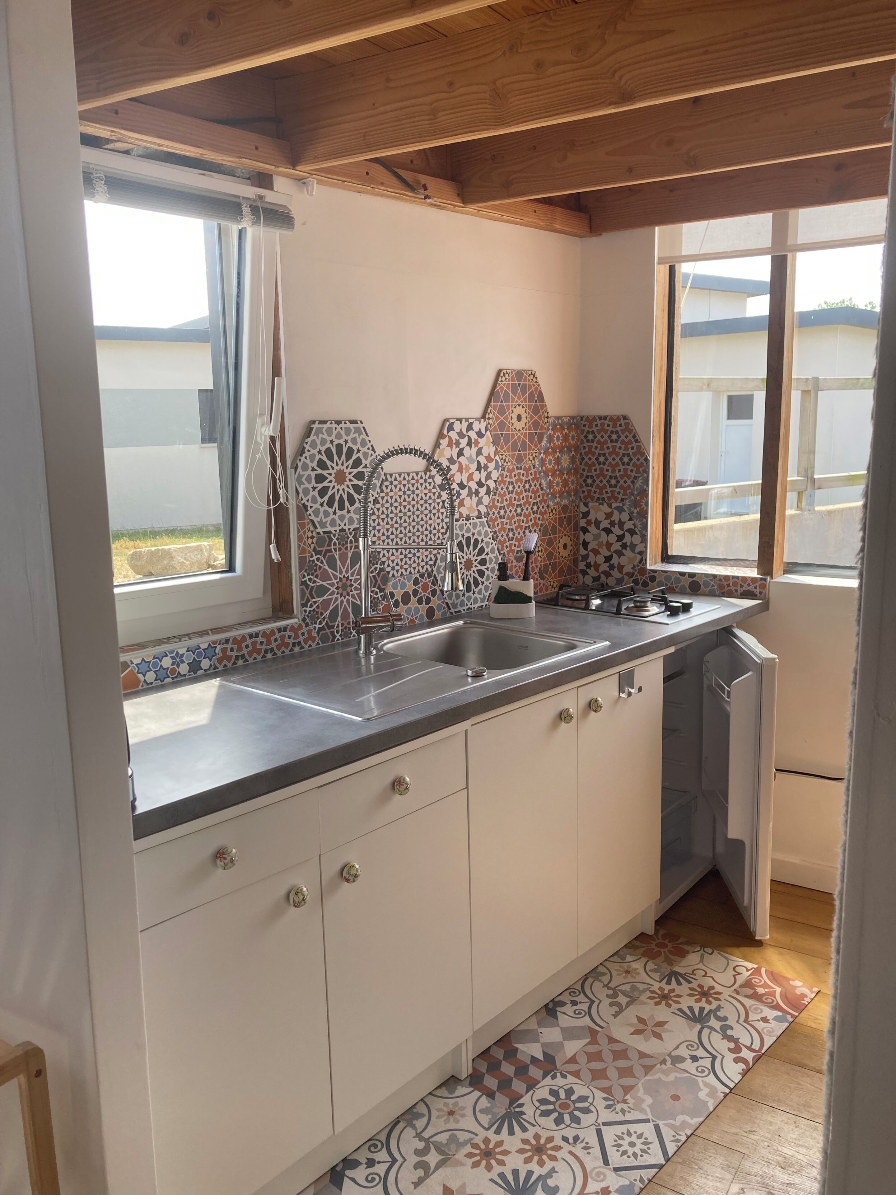 A kitchen with a sink, cabinets, and a patterned backsplash.