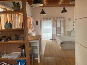 A room with a bed, a desk, and a shelf with kitchenware. - L'atelier, 800 meters from the sea, unique lodging in an old neighborhood (Plouescat)