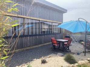 An outdoor seating area with a table and chairs, a blue umbrella, and a wooden fence. - L'atelier, 800 meters from the sea, unique lodging in an old neighborhood (Plouescat)