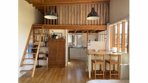 Una habitación estilo loft con escalera de madera, comedor y cocina.