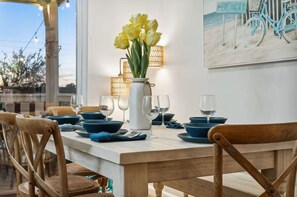 Ein Esstisch, gedeckt mit blauen Schalen, Weingläsern und einer Vase mit gelben Blumen.