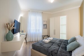 A bedroom with a bed, a desk, a chair, a wardrobe, and a window with curtains. - Elegant design, 3 bedrooms, 2 bathrooms, bright (Firenze)