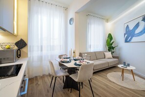 A modern living room with a dining area, a sofa, a coffee table, and a large abstract painting on the wall. - Elegant design, 3 bedrooms, 2 bathrooms, bright (Firenze)