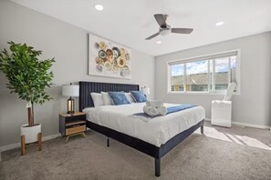 A bedroom with a bed, a ceiling fan, a window, a plant, and a wall art piece. - Spacious 5-bedroom house in tranquil Calgary perfect for families (Calgary)