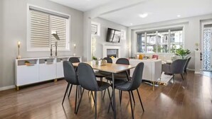 Un comedor moderno con una mesa de madera y sillas negras, una consola blanca con objetos decorativos y una chimenea.