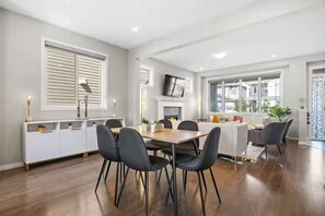 A modern dining area with a wooden table and black chairs, a white console table with decorative items, and a fireplace. - Spacious 5-bedroom house in tranquil Calgary perfect for families (Calgary)