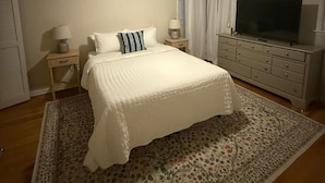 Un dormitorio con cama, televisor, ventilador de techo y cómoda.