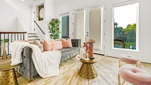 Un salon moderne avec un escalier, un canapé, une table basse et une vue sur l’extérieur.