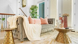 Un salon avec un canapé gris, un plaid blanc et une table basse sur laquelle se trouve un vase.
