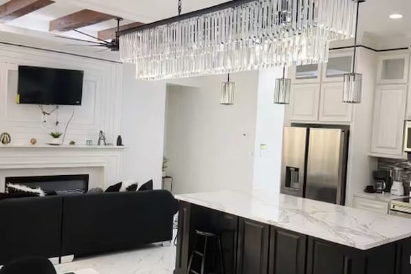 A modern kitchen with a marble island, stainless steel appliances, and pendant lighting.